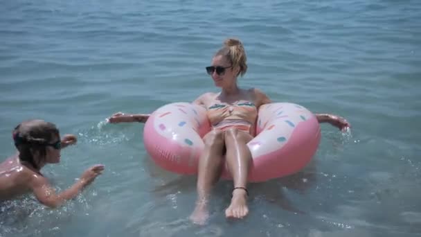 Οικογενειακή χαλάρωση σε φουσκωτό παιχνίδι ντόνατ, κολύμπι στη γαλάζια θάλασσα — Αρχείο Βίντεο