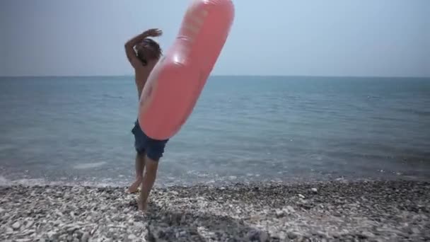 Un niño feliz va a nadar en el mar azul. — Vídeo de stock