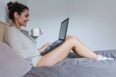 Kahve içer ve dizüstü bilgisayarda çalışan genç kadın