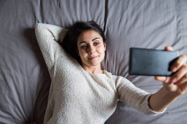 genç kadın yatakta bir selfie alarak