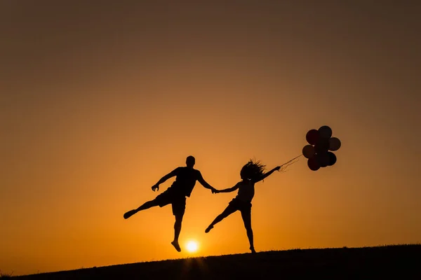 Silhouette di una coppia che gioca con palloncini al tramonto — Foto Stock