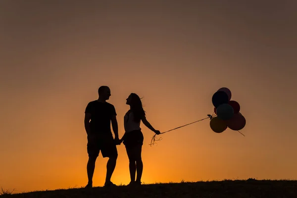 Siluet dari pasangan bermain dengan balon saat matahari terbenam — Stok Foto