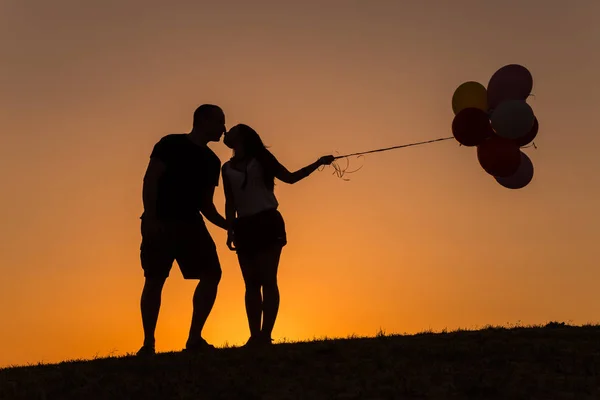 Siluet dari pasangan bermain dengan balon saat matahari terbenam — Stok Foto