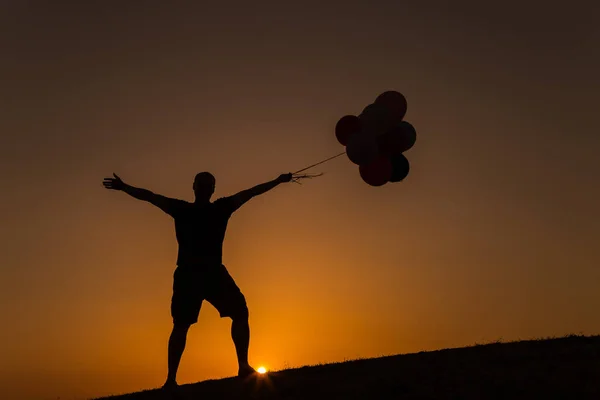 Siluet seorang pria bermain dengan balon saat matahari terbenam — Stok Foto