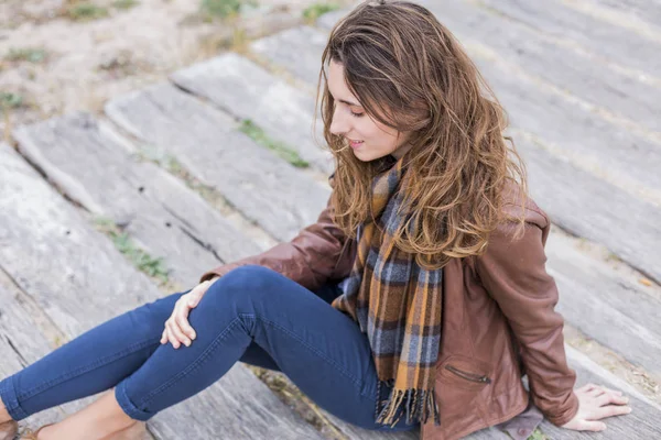 Utomhus porträtt av en ung kvinna med brun jacka, jeans och — Stockfoto