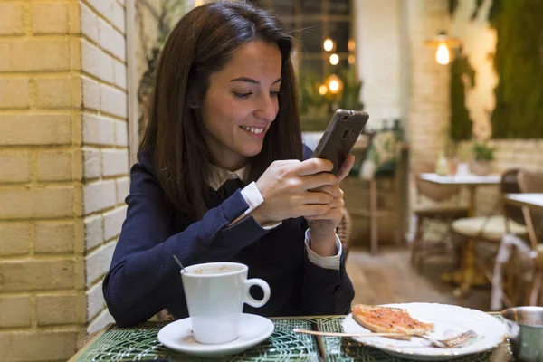 Wanita muda menggunakan smartphone saat breakgast — Stok Foto