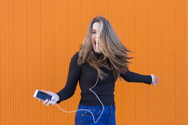 Wanita muda yang cantik mendengarkan musik dengan earphone dan havi — Stok Foto