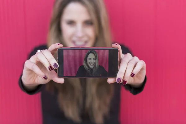 Beautiful young woman taking a picture with a smartphone over re — Stock Photo, Image