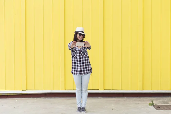 Happy beautiful woman taking a selfie with smartphone over yello — Stok Foto