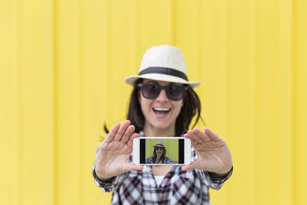 Ευτυχής όμορφη γυναίκα που αναλαμβάνει μια selfie με smartphone yello Royalty Free Εικόνες Αρχείου