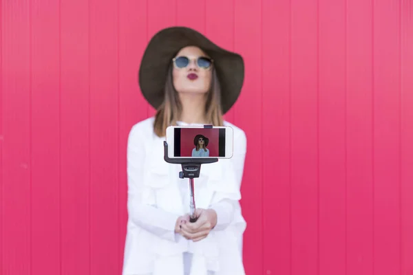 Happy beautiful woman taking a selfie with smartphone over red b — Stock Photo, Image