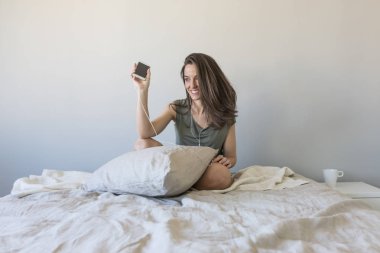 Yatağın üstüne oturan ve müzik güzel ve genç birbayan. Eğlenceli