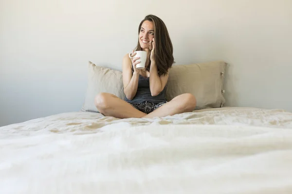 Belle jeune femme appréciant le café sur le lit — Photo