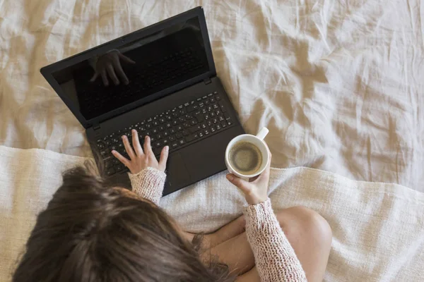 Piękna młoda kobieta siedzi na łóżku za pomocą laptopa i ciesząc się h — Zdjęcie stockowe