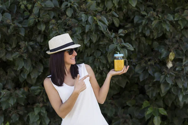 Wanita muda yang cantik menikmati jus jeruk di luar ruangan. b hijau — Stok Foto