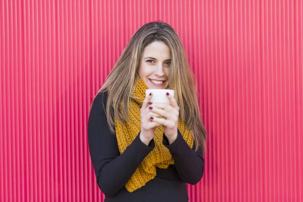 Wanita muda yang cantik memegang secangkir kopi. Latar merah — Stok Foto