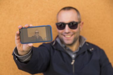 mutlu yakışıklı adam akıllı telefonunu bir resimle devralarak veya