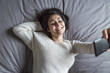 bir selfie bir akıllı telefon ile yatağa alarak güzel genç kadın 