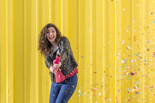 Young woman having fun with confetti over yellow background — Stock Photo, Image