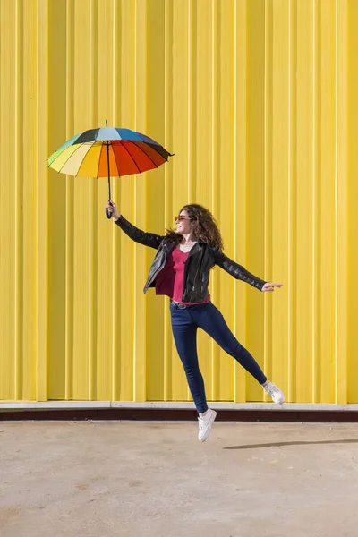 Jovem mulher pulando e se divertindo com um ove guarda-chuva colorido Fotos De Bancos De Imagens Sem Royalties