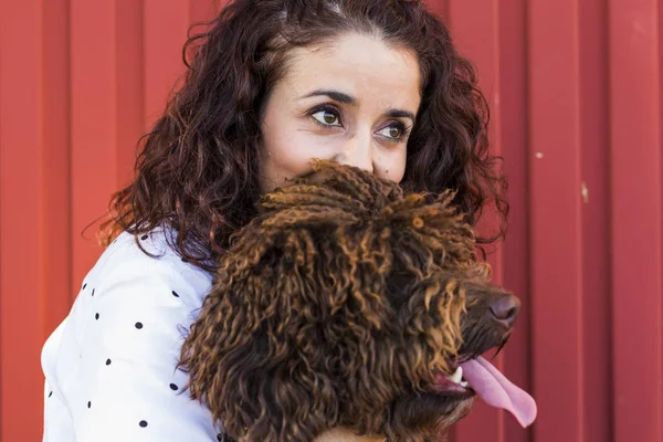 Wanita muda yang cantik memeluk anjingnya, anjing air Spanyol berwarna coklat — Stok Foto