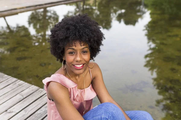 Retrato de um feliz jovem bela afro-americana mulher sentada Imagens De Bancos De Imagens Sem Royalties