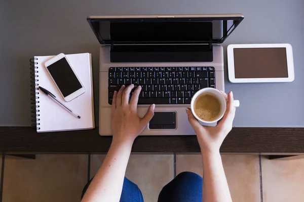 Kahve, smartpho ile dizüstü bilgisayar üzerinde çalışan kadın Üstten Görünüm