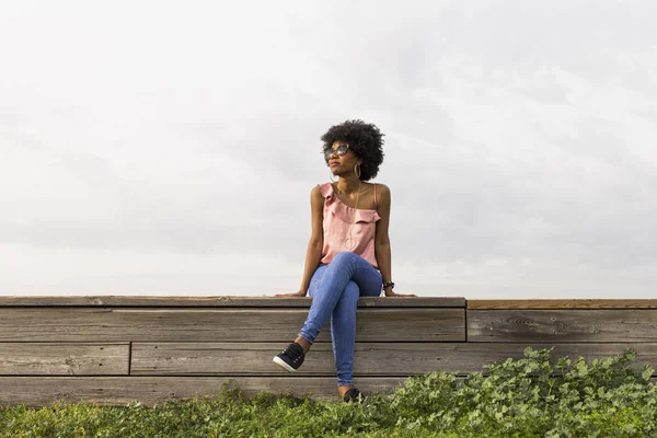 Πορτραίτο μια ευτυχισμένη νεαρή όμορφη afro Αμερικανός γυναίκα κάθεται Εικόνα Αρχείου