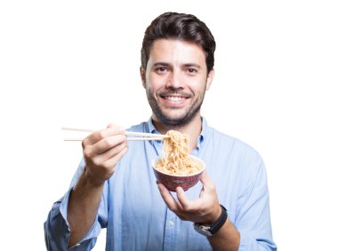 Genç adam beyaz arka planda suşi yiyor.