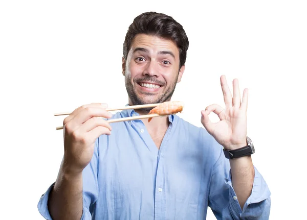 Junger Mann isst Sushi auf weißem Hintergrund — Stockfoto