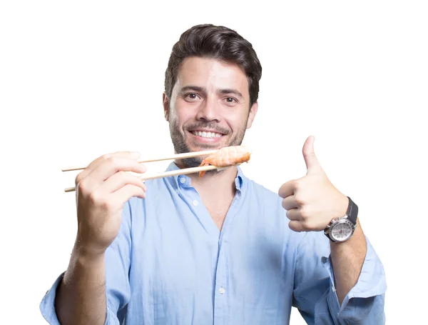 Junger Mann isst Sushi auf weißem Hintergrund — Stockfoto