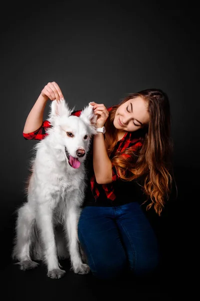 Portrait of a young teenager girl with her dog in studio on a black background — Stock Photo, Image