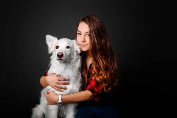 Portrait of a young teenager girl with her dog in studio on a black background — Stock Photo, Image