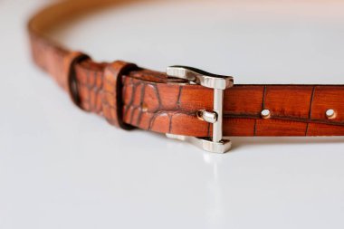 beyaz zemin üzerine metal toka ile kahverengi deri kayış 