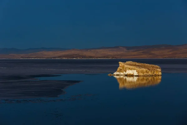 Pequeña isla rocosa en el lago Baikal con su reflejo con hielo derretido —  Fotos de Stock