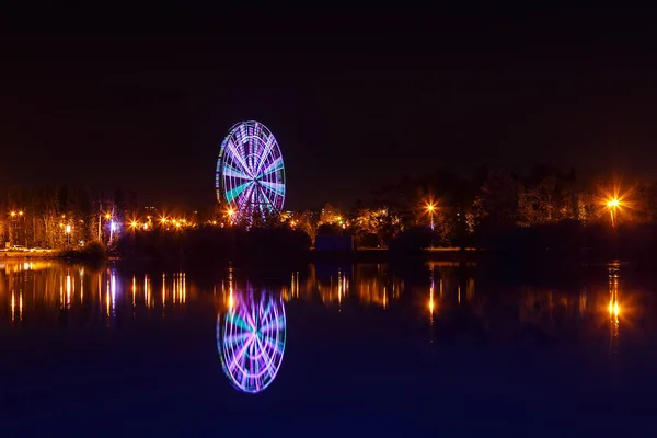 Rueda de observación iluminada por la noche reflejada en el agua — Foto de Stock