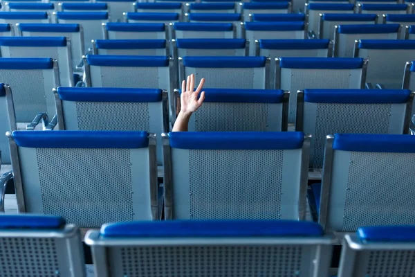 Fila de asientos y una mano humana en gesto de ayuda en la sala del aeropuerto — Foto de Stock