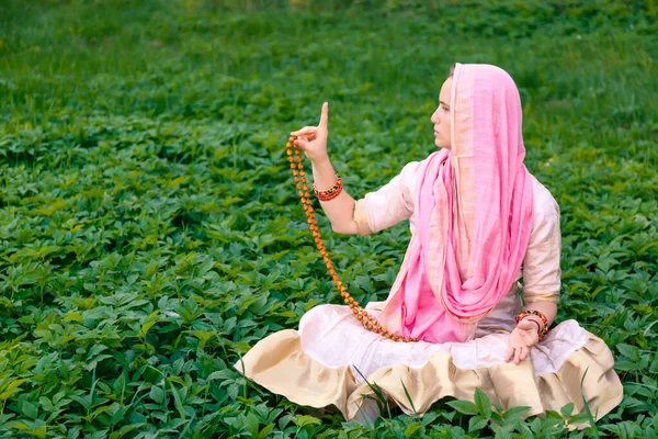 女性でインドの白とピンクの服に座って瞑想姿勢で緑の草原 — ストック写真
