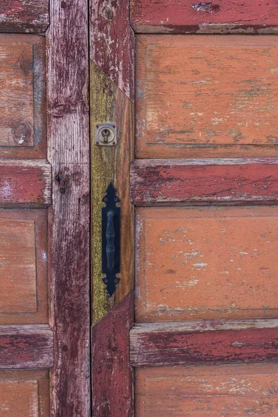 Ușă veche din lemn vopsită în culori calde cu mâner de fier . — Fotografie, imagine de stoc