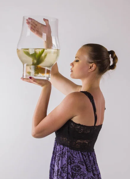 Jovem mulher olhando cuidadosamente em um aquário com peixinho dourado — Fotografia de Stock