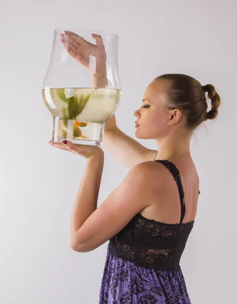 Jovem mulher olhando carinhosamente em um aquário com peixinho dourado . — Fotografia de Stock