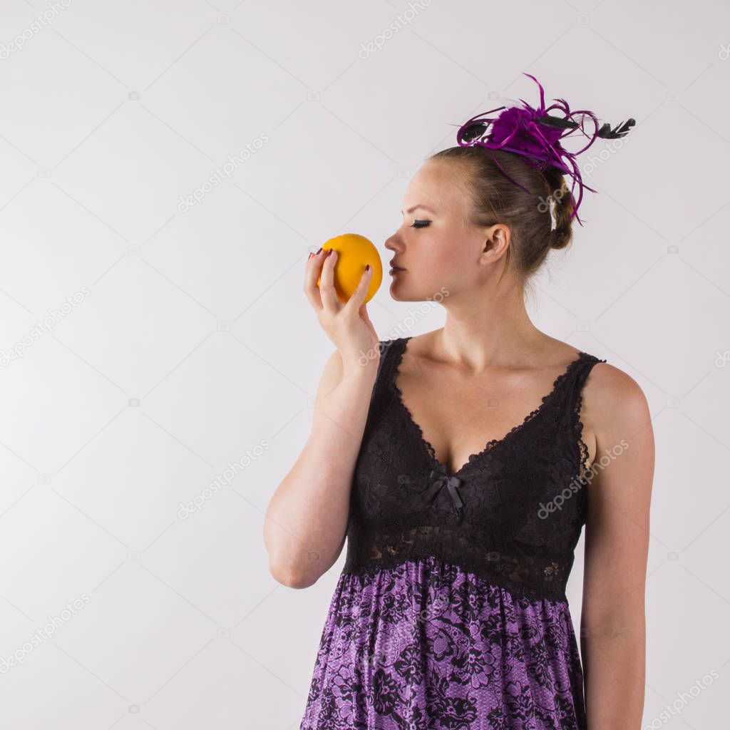 Tender brunette woman in violet lingerie sniffing odorous orange
