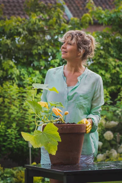 Mulher atraente processa vegetais em seu jardim olhando para cima . — Fotografia de Stock