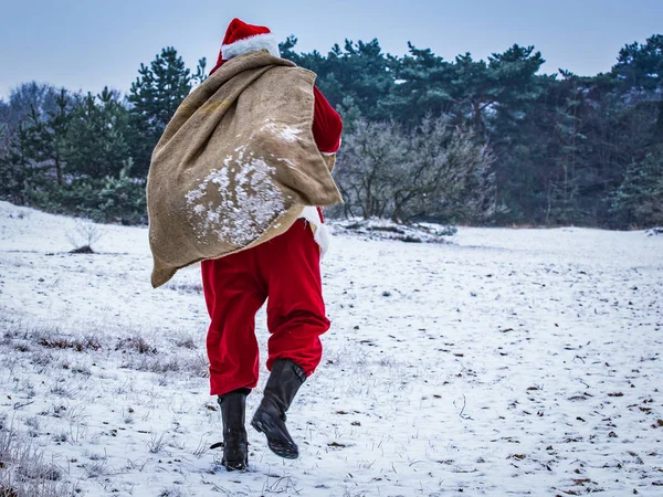 Noel Baba hediye karla kaplı alanda bir çanta ile