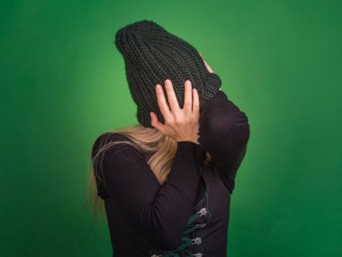 Kadın yüzünü örme şapka ile kapsar ve arkasını dönüyor