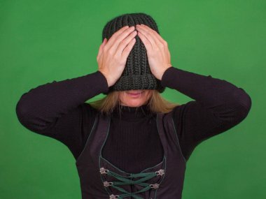 Genç kadın yüzünü örme şapka ile kapsar 