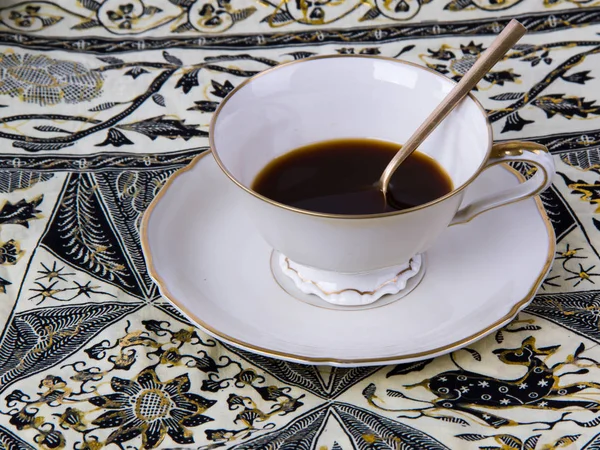 A Cup of Coffee on Indonesian Ornamental Backgroundon. — Stock Photo, Image