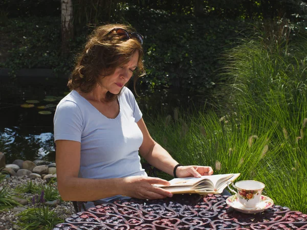 Женщина средних лет, читающая книгу с концентрацией в гарде — стоковое фото
