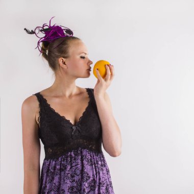 Tender brunette woman in violet lingerie sniffing odorous orange clipart