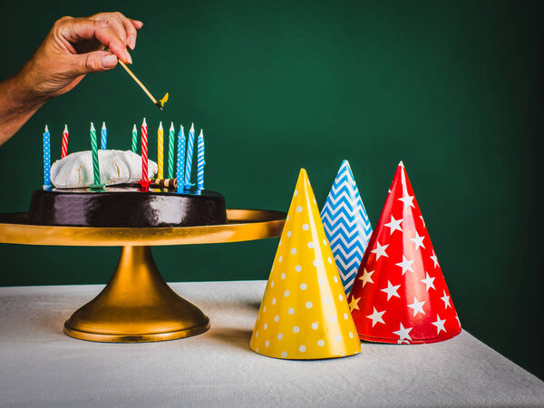 Рука женщины зажигает свечи на торте
.